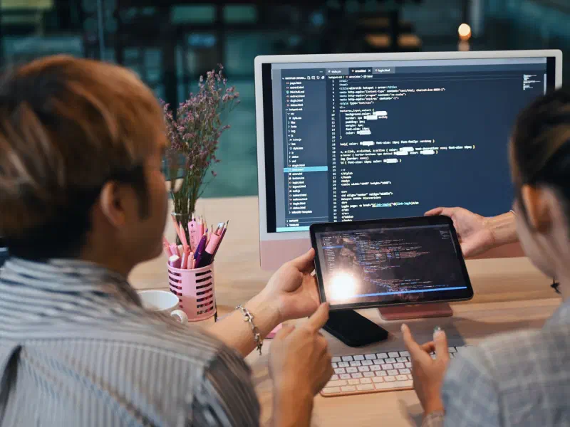 Team of developers reviewing code on a monitor and tablet together